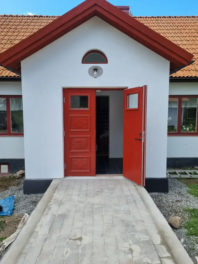 Platsbyggd entrédörr i trä på vitputsat hus i Kivik